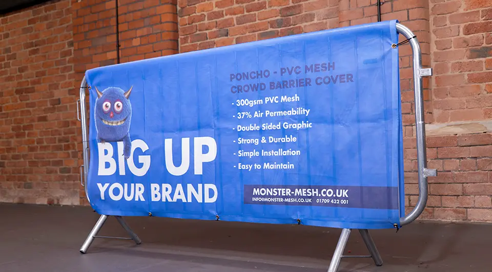 Best Crowd Barrier Covers for Your Budget 4 A blue Poncho style PVC mesh crowd barrier cover draped over a metal barrier, showing how the material hangs over the top bar without a fitted side sleeve.