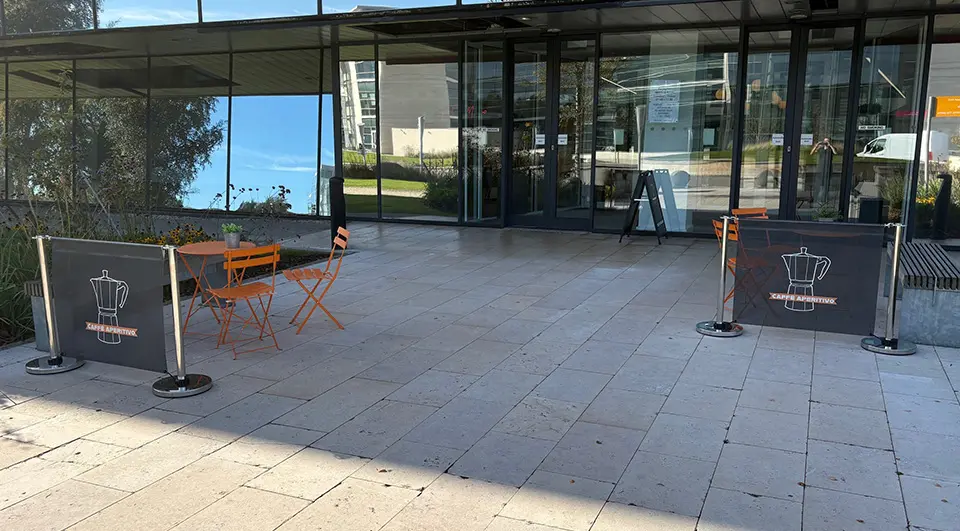 Café Barriers for Caffé Aperitivo 1 Branded café barriers for Caffè Aperitivo flanking an outdoor seating area at White Rose Office Park in Leeds