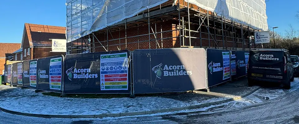 Heras Fence Covers for Acorn Builders 4 A panoramic view of a residential corner plot under construction, surrounded by scaffolding and wrapped in black Acorn Builders Heras fence covers