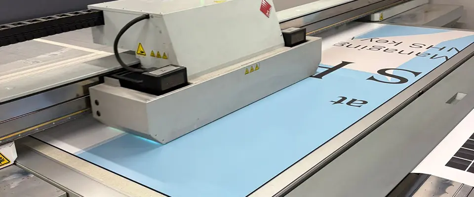 Full Service Hoarding Signage for Nevada Construction 4 A large-format flatbed printer printing text onto a light blue ACM Dibond panel for the Nevada Construction hoarding signage.