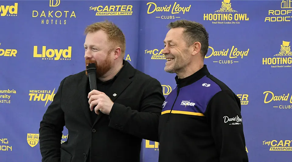 Custom Banners for Newcastle Thunder Rugby League 3 Close-up shot of two men standing in front of a purple media interview backdrop banner covered in yellow sponsor logos, including Dakota Hotels, Lloyd Motor Group, and David Lloyd Clubs.