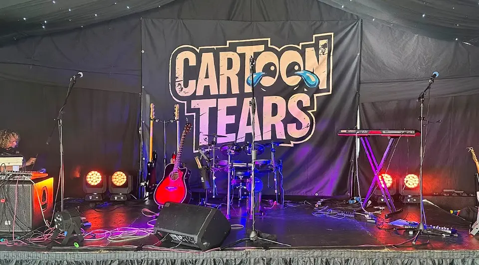 7 Band Backdrop Ideas that actually work on stage 21 Cartoon Tears band backdrop hung on a frame behind a full stage setup in a marquee
