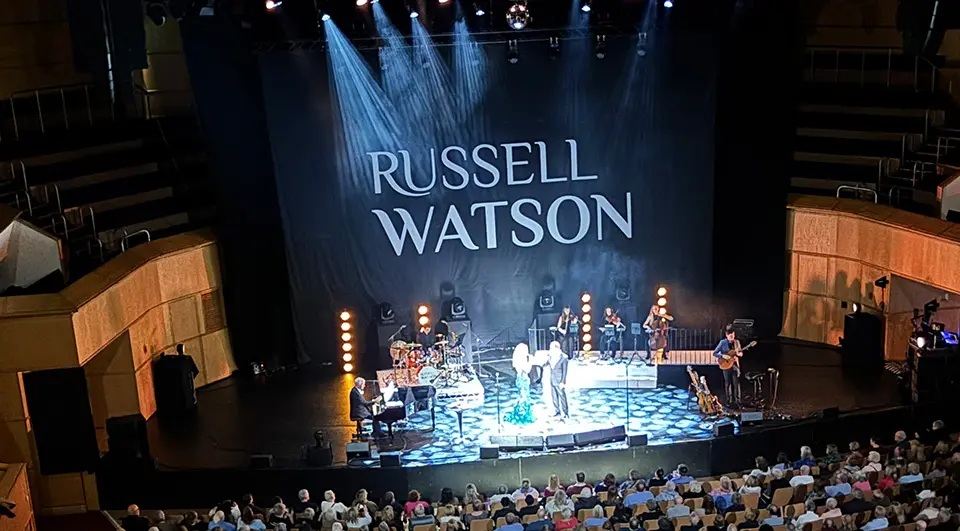 Russell Watson stage backdrop with his name in white lettering on black at a large theatre show